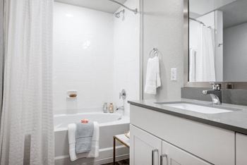 a white bathroom with a tub and a sink and a mirror